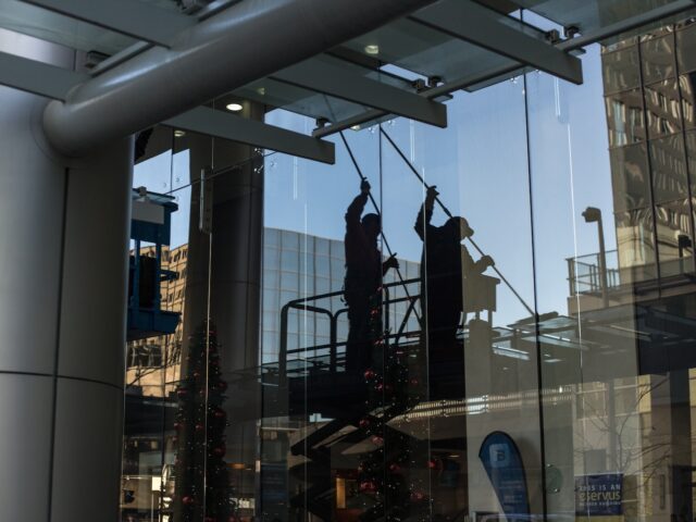 utility man standing in scissor platform cleaning glass window