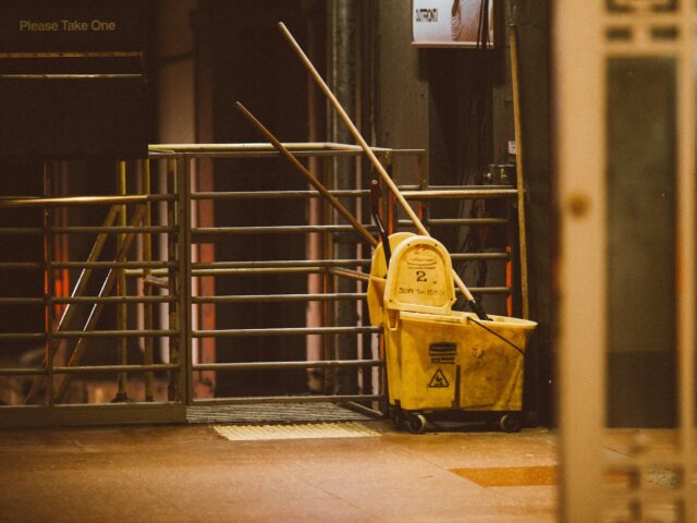 yellow plastic trash bin beside black metal stair railings